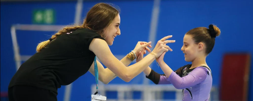 Entrenadora animant gimnasta artística
